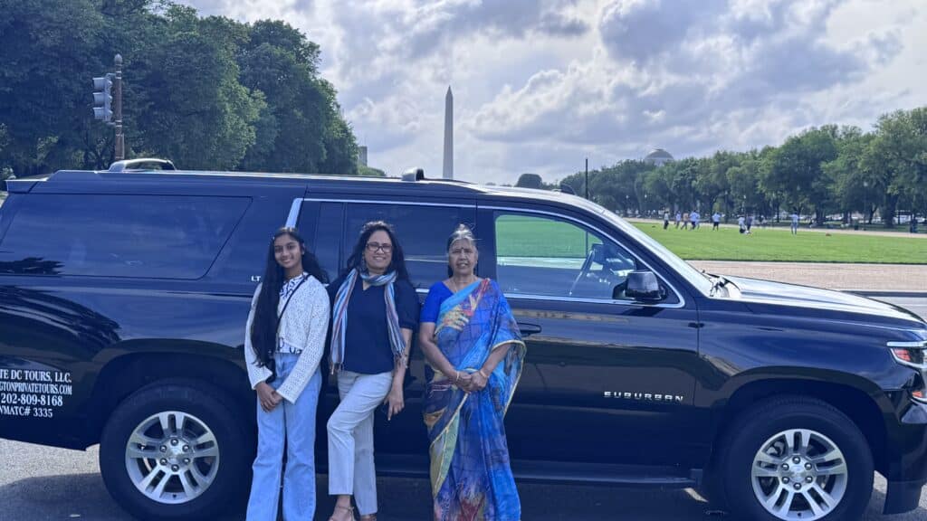 Family enjoying a private tour at the National Mall in Washington, DC with a luxury Chevrolet Suburban and the Washington Monument in the background